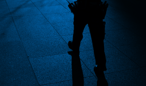 legs of a security guard at night walking down a sidewalk