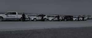 six fleet vehicles parked on the side of the road with security guards standing in front of each