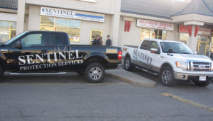 two sentinel protection services trucks, one white and one black