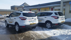 two white sentinel security suvs parked in snowy parking lot
